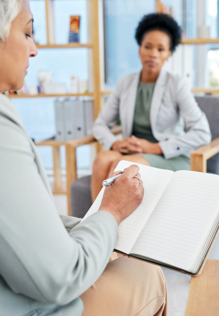 Woman in therapy and therapist writing, counseling and psychology evaluation, therapy support or he